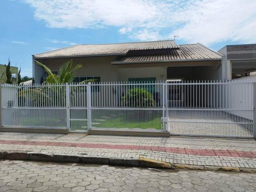 a white fence in front of a house at Casa com piscina em Zimbros in Bombinhas
