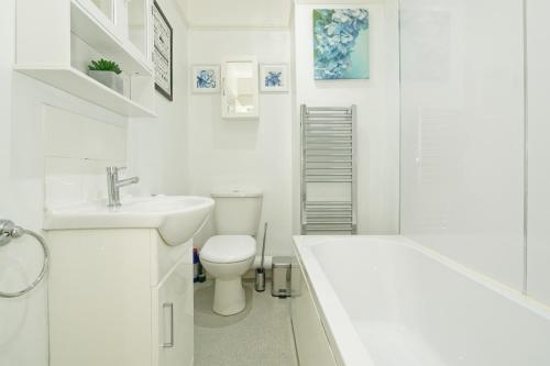 a white bathroom with a toilet and a sink at Lovely Luxury 3 Bed House in Chatham