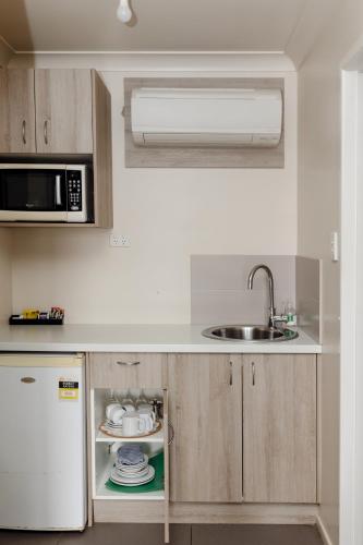 a small kitchen with a sink and a microwave at Starline Motor Inn in Miles