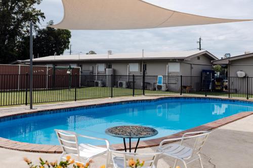 a swimming pool with chairs and a table in front of a building at Starline Motor Inn in Miles