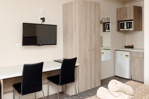 a kitchen with a desk with chairs and a tv at Starline Motor Inn in Miles