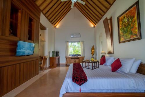 a bedroom with a white bed and a tv at Lawira Beach Villa Lovina in Lovina