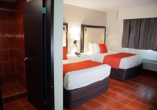 a hotel room with two beds and a shower at Del Mar Inn Playas in Tijuana