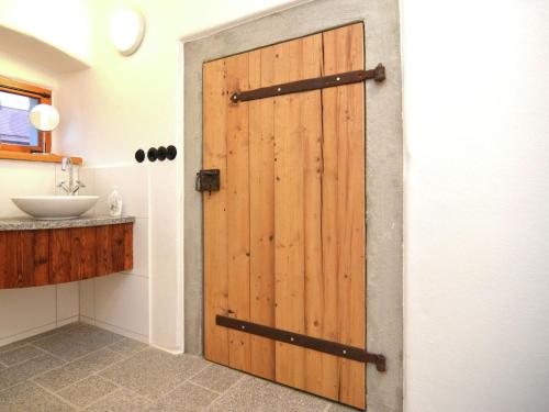 eine Holztür im Bad mit Waschbecken in der Unterkunft Sunny holiday home near the forest in Stadlern