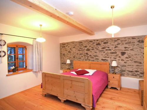 ein Schlafzimmer mit einem Bett und einer Steinmauer in der Unterkunft Sunny holiday home near the forest in Stadlern