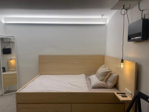 Bett mit einem Kopfteil aus Holz in einem Zimmer in der Unterkunft The Nano Pad - small, smart, central in Köln