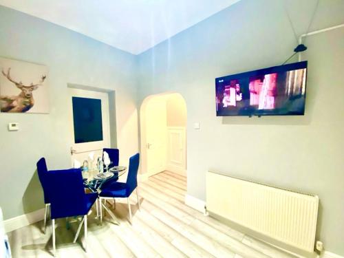 uma sala de jantar com uma mesa e uma televisão na parede em One Bedroom Ground Floor Flat In Central London em Londres