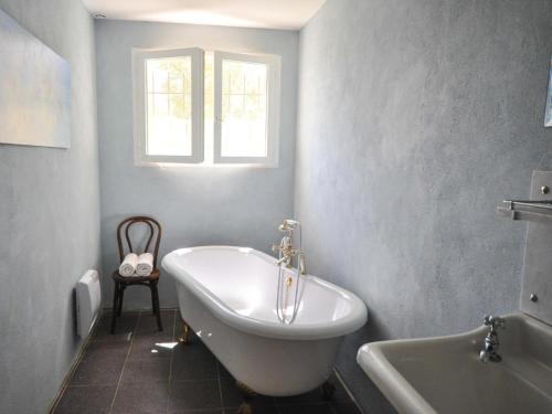 uma banheira branca na casa de banho com uma janela em Villa au calme avec piscine em Cazedarnes