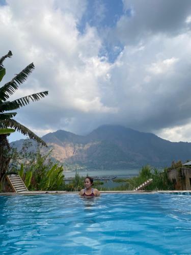 a woman in a swimming pool with mountains in the background at Volcano Living in Kintamani