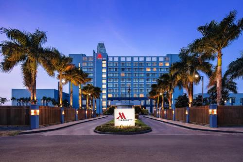 a sign in front of a building with palm trees at Guyana Marriott Hotel Georgetown in Georgetown
