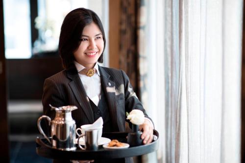 a woman in a suit holding a tray of food at The St. Regis Bangkok in Bangkok