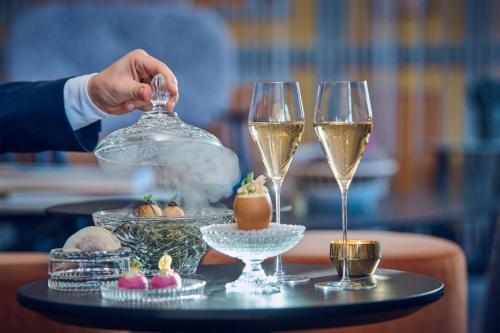 a person is holding a spoon and two glasses of wine at The St. Regis Bangkok in Bangkok