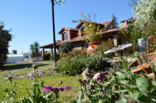 a garden with flowers in front of a house at Cabañas La Aldea in Villa Carlos Paz