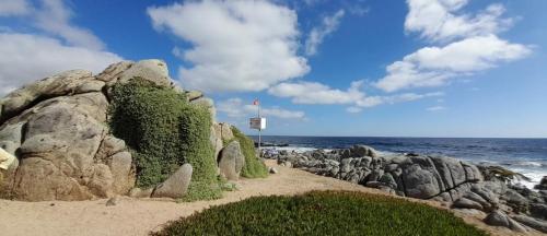 um grupo de rochas na praia perto do oceano em Cabañas Isla Neruda em El Quisco