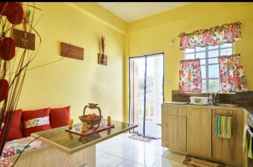 a kitchen with yellow walls and a table in a room at Isla Vista Apartment Canouan #2 in Canouan