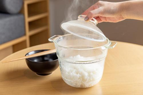 a person pouring rice into a glass container on a table at Tokyu Stay Tsukiji - Tokyo Ginza Area in Tokyo