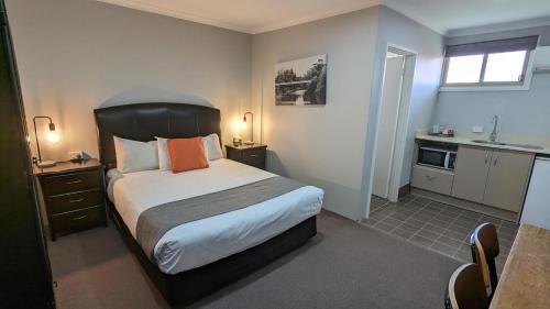 a small bedroom with a bed and a kitchen at River Motel in Queanbeyan