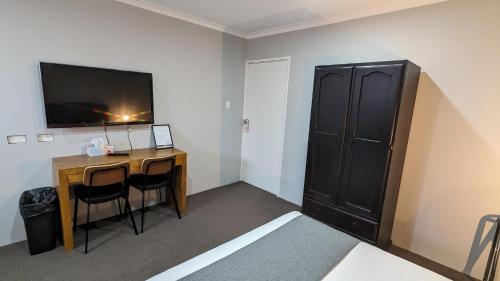a room with a desk with a computer and a tv at River Motel in Queanbeyan