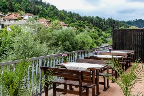 a deck with tables and benches on a balcony at Бялата къща in Zlatograd