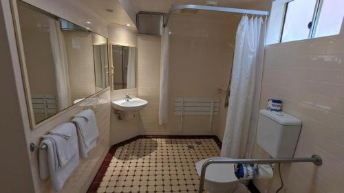 a bathroom with a shower and a toilet and a sink at River Motel in Queanbeyan