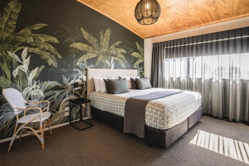 a bedroom with a large bed with a tropical wallpaper at Ohope Beach TOP 10 Holiday Park in Ohope Beach