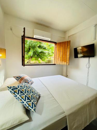 a bedroom with a large white bed with a window at CASINHA FLOR, no centro histórico!!! in Piranhas