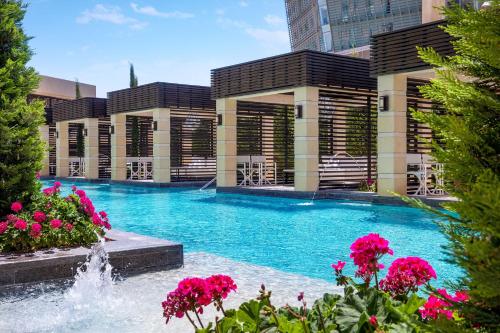 a swimming pool with pink flowers in front of a building at The St. Regis Amman in Amman