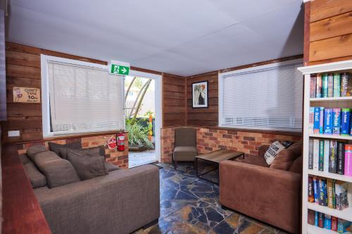 una sala de estar con 2 sofás y un estante para libros. en Cairns City Backpackers Hostel, en Cairns