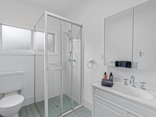 La salle de bains blanche est pourvue d'une douche et de toilettes. dans l'établissement Piri at Pearl Autumn Special, à Pearl Beach