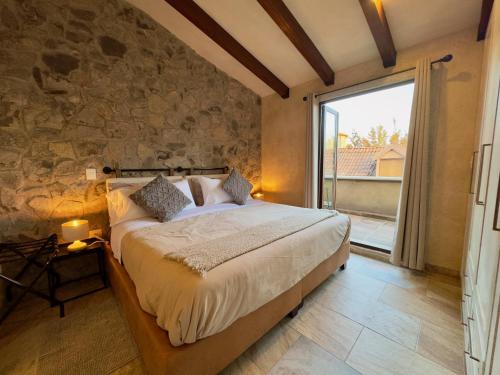 a bedroom with a large bed with a stone wall at Loft Arena en ValQuirico in Santeagueda