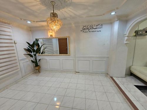 a living room with a chandelier and a white tile floor at Ruhani Homestay 3 KB - 4 Bedroom Fully Airconditioned with WIFI & Netflix in Kota Bharu