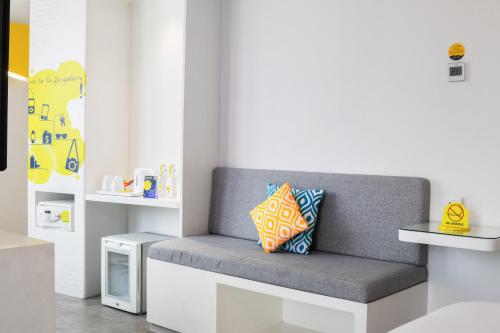 a gray bench with two pillows on it in a room at YELLO Hotel Kuta Beachwalk Bali in Kuta