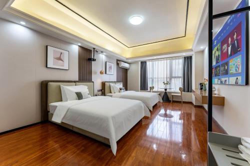 two beds in a room with wooden floors at East Maple International Apartment - Guangzhou Luogang Wanda Plaza Suyuan Metro Station in Guangzhou