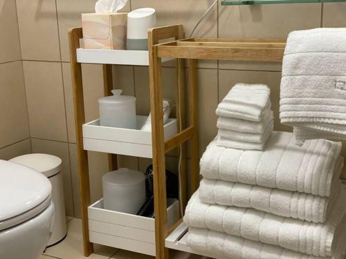 a bathroom with a stack of towels and a toilet at Boxwood IXL Lux Hobart Waterfront in Hobart
