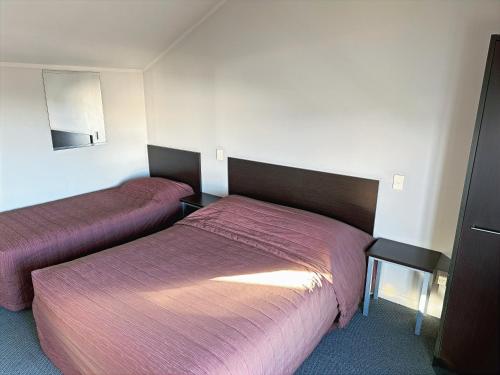 a hotel room with two beds with pink sheets at Arena Lodge in Palmerston North