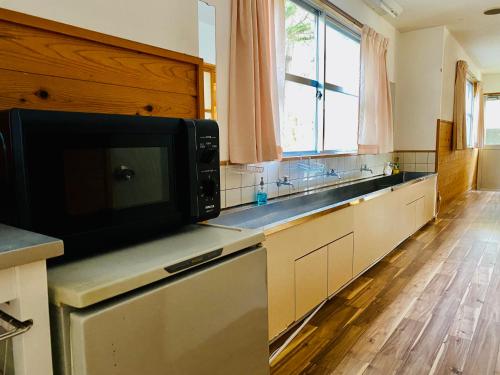 Ōdoにある山茶小屋 Yamachagoyaのシンクと電子レンジ付きのキッチン