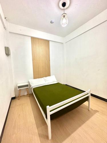 um quarto com uma cama com um cobertor verde em Zz Dormitel em Nabua