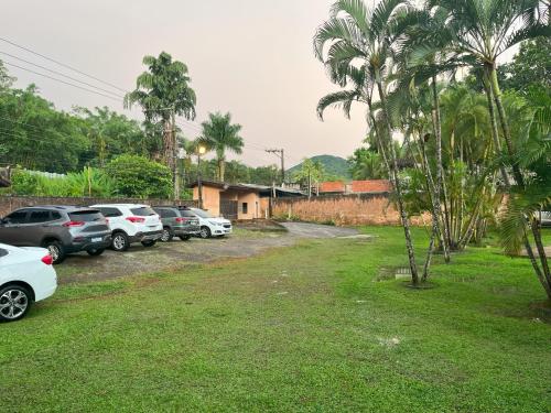 een rij geparkeerde auto's geparkeerd in een tuin bij Camburi Chalés in Camburi