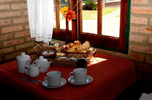 a table with cups and a basket of food on it at Cabañas La Aldea in Villa Carlos Paz