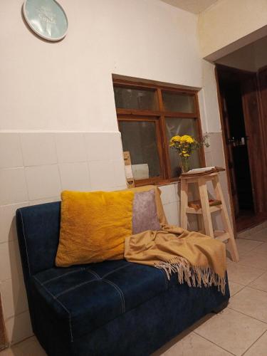 Un sofá azul con una manta amarilla. en Centric Room, en Riobamba