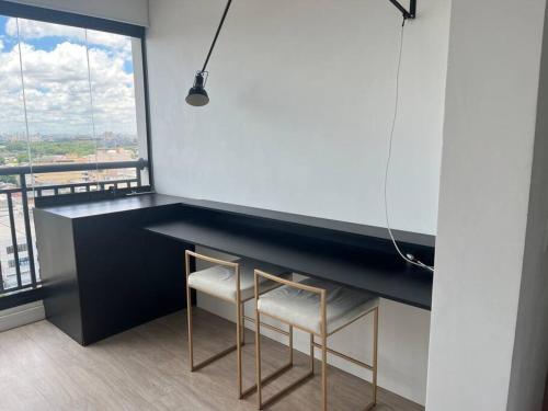a kitchen with a black counter and two stools at Studio Amplo Linda Vista SP/Allianz/ Sambódromo in Sao Paulo