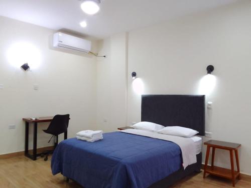 ein Schlafzimmer mit einem Bett mit einer blauen Decke und einem Schreibtisch in der Unterkunft Gran Imperial Avenida in Tumbes