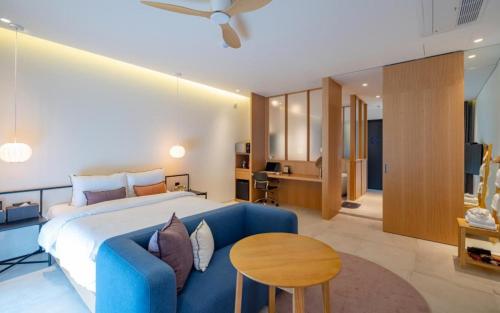 een slaapkamer met een groot bed en een blauwe bank bij Hotel Barahan Jeonju in Jeonju
