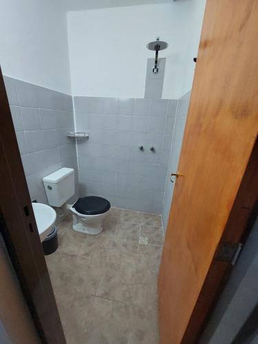 baño con aseo y asiento negro en El Descanso, en Villa Unión