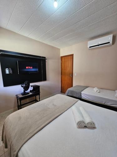 a bedroom with two beds and a tv on the wall at Arembepe - Aldeia St Sebastien Casa Mar 10 in Camaçari