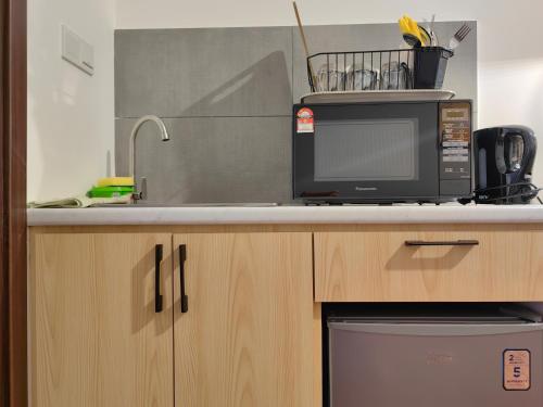 a kitchen counter with a microwave and a sink at Near Airport K Avenue Family Room in Donggongon