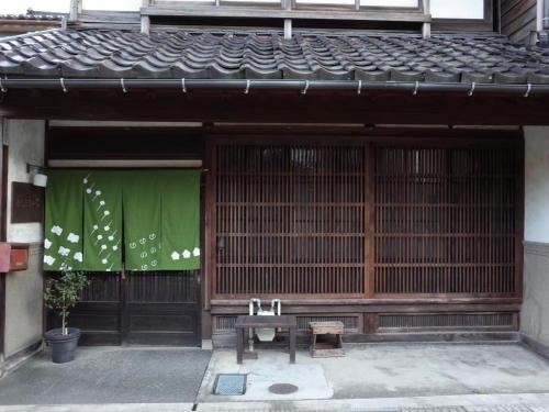 a bench in front of a building with a green banner at （一棟貸切）町家体験ゲストハウス「ほんまちの家」〜高岡市の伝統的な古民家～ in Yokota