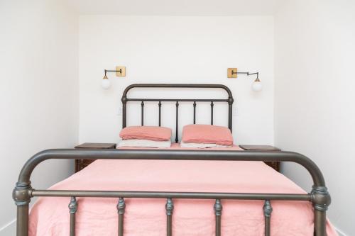 a metal bed with pink sheets and pillows on it at Bright 3 bedroom house Downtown in Toronto