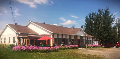 a house with pink flowers in front of it at Gîte du Moulin in L'Isle-aux-Coudres