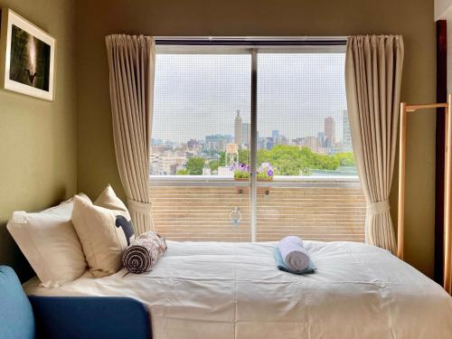 a bed with two hats on it in front of a window at 新宿区早稻田地铁6分钟两室景观公寓 in Tokyo